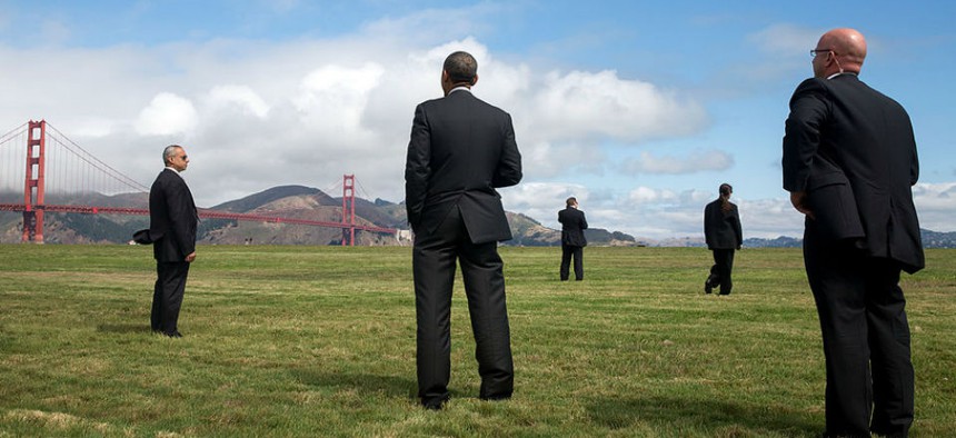 President Obama  stands with U.S. Secret Service agents and looks at the Golden Gate Bridge, prior to boarding Marine One at the Crissy Field landing zone for departure from San Francisco on July 23, 2014.