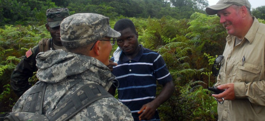 U.S. military personnel discuss construction details with a Liberian contractor at the future location of an Ebola treatment unit in Liberia.
