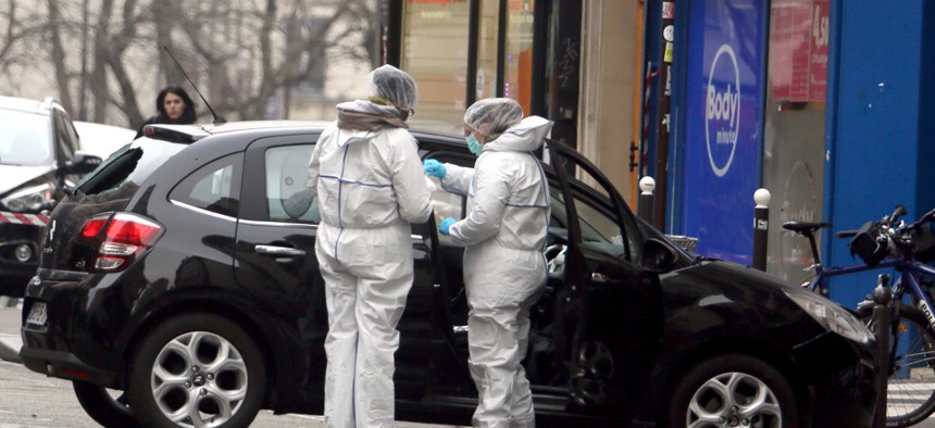 Forensic experts examine the car believed to have been used as the escape vehicle by gunmen in Paris Wednesday.