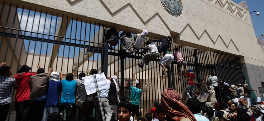 Yemeni protestors climb the gate of the U.S. Embassy in 2012.
