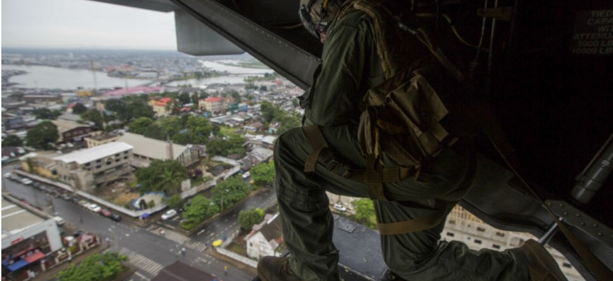 U.S. Marine Corps Cpl. Anthony Kite looks out of an MV-22B Osprey as it prepares to land at the U.S. Embassy in Monrovia, Liberia, to support Operation United Assistance. 