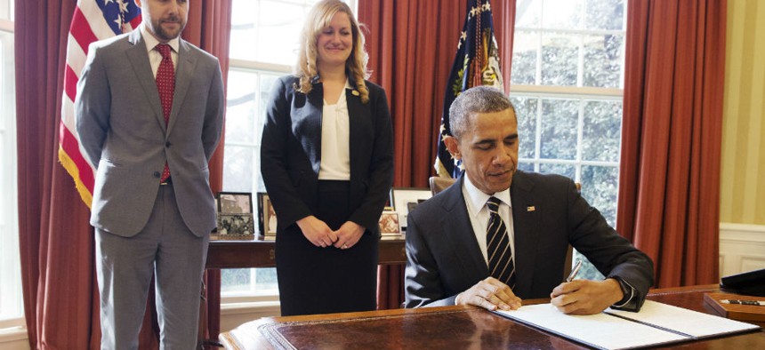 Obama signs the executive order, as Senior Adviser Brian Deese and Federal Chief Sustainability Officer Kate Brandt look on.