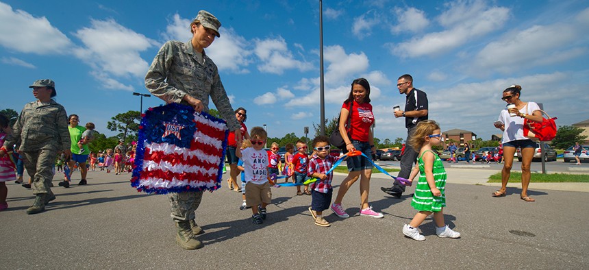 Children, parents, and employees of the Child Development Center East march around the parking lot during a parade in honor of Flag Day on Hurlburt Field in 2013.