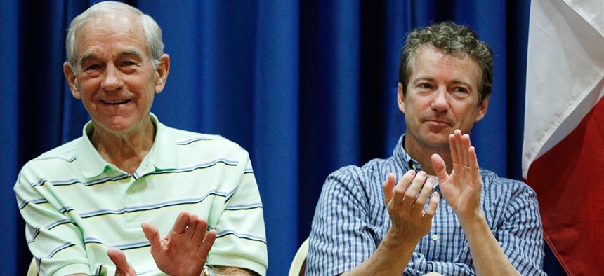 Rep. Ron Paul, R-Texas, left, and his son, Sen. Rand Paul, R-Ky., applaud on stage at a campaign event in Iowa in 2011.