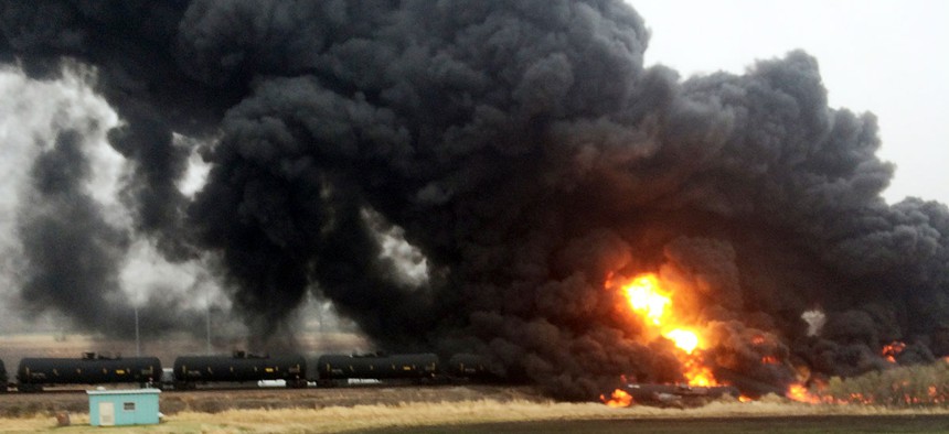 A train spews smoke and fire after it derailed, May 6, in Heimdal, N.D.