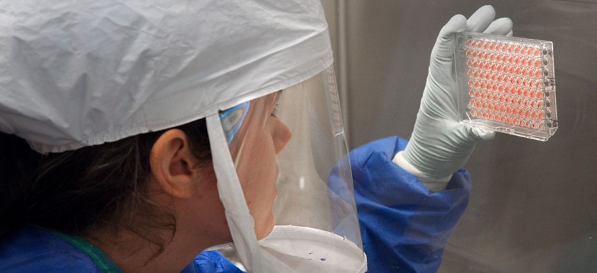 A female CDC scientist works with a bird flu sample in 2013.