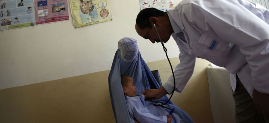 In this 2011 photo, a doctor uses a stethoscope on a child held in the arms of his mother at a health clinic in Kabul.