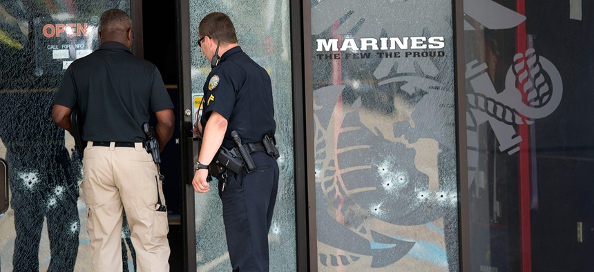 Police officers enter the Armed Forces Career Center through a bullet-riddled door after the shooting Thursday.