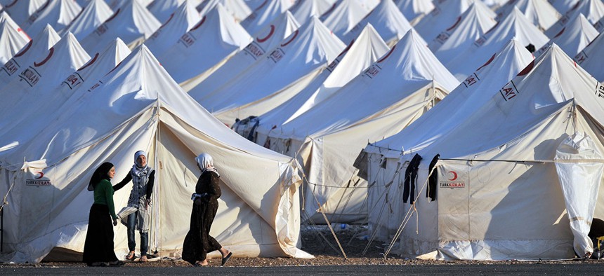 Refugees stand outside a camp on the Syrian-Turkish border in 2011.