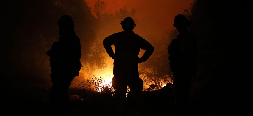 Firefighters watch as the flames of the Butte Fire approach a containment line near San Andreas, Calif., Sept. 11, 2015.