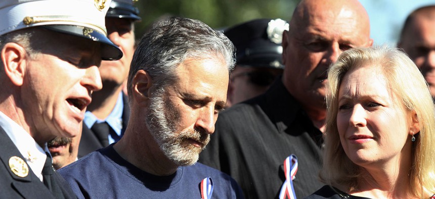 Jon Stewart and Sen. Kirsten Gillibrand stand with New York City first responders during a rally on Capitol Hill