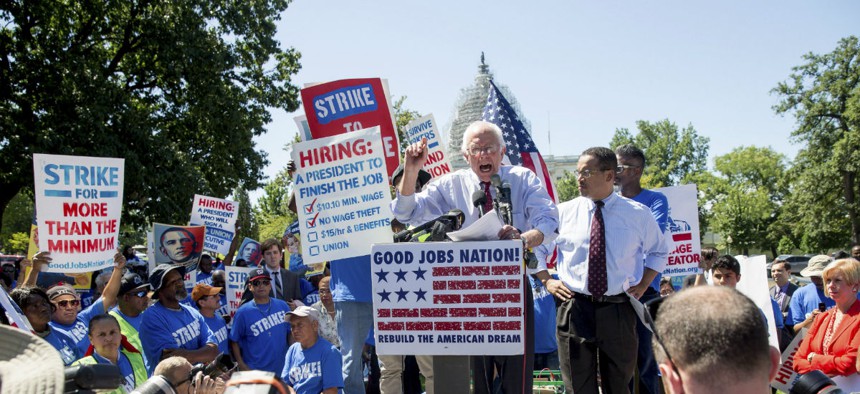 Democratic presidential candidate Sen. Bernie Sanders, I-Vt., joined by Rep. Keith Ellison, D-Minn., at right, and federal contract workers, speaks during a rally on Capitol Hill July 22 to push for a raise in the minimum wage.