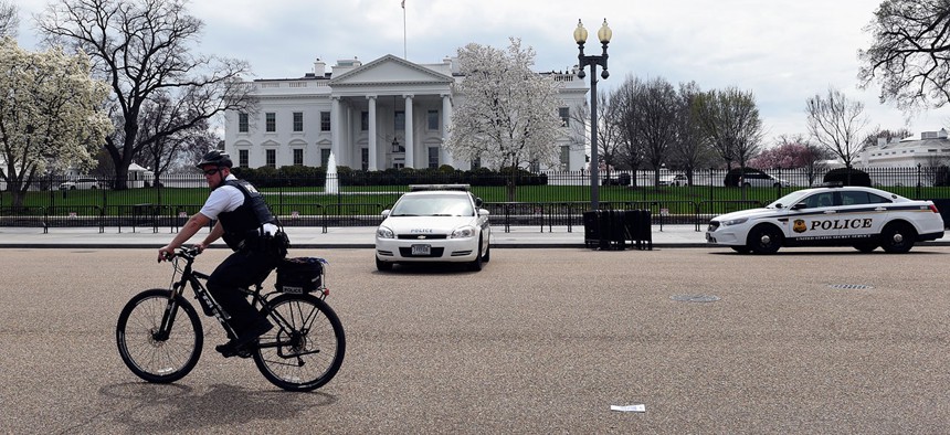 A Secret Service agent rides his bike on Pennsylvania Avenue outside the White House in April.