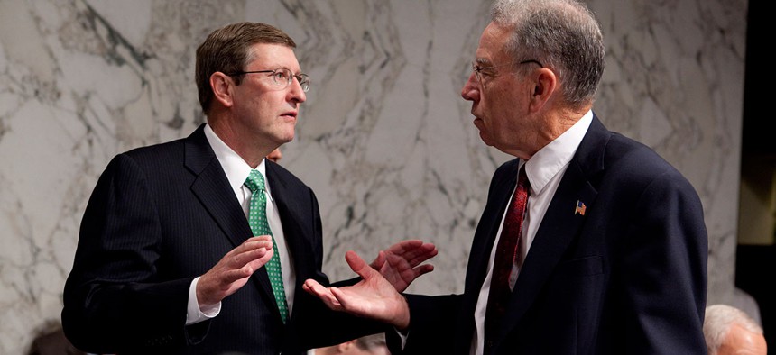 Then-Sen. Kent Conrad talks with Sen. Chuck Grassley prior to the start of a hearing on health care reform legislation in 2009. Sen. Orrin Hatch is seated at right.