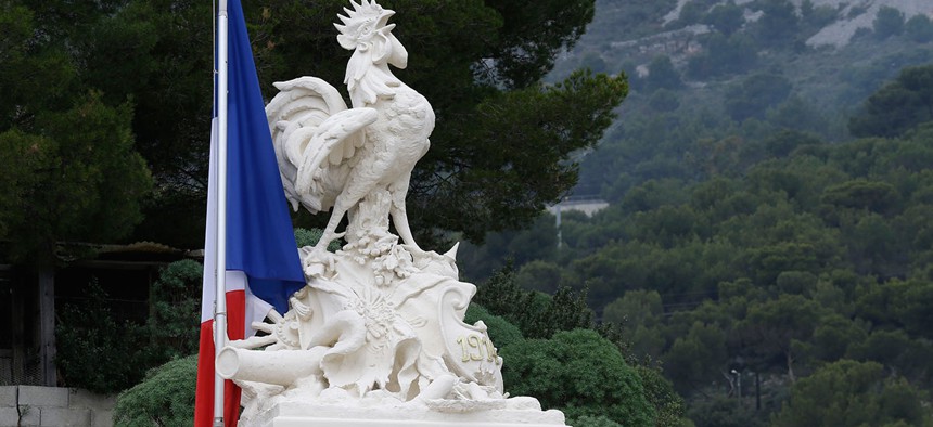 A French flag flies at half-mast by a symbol for France, the Gallic rooster, on the top of a war memorial in a cemetery in tribute to the victims of last Friday's attacks in Paris, in Beausoleil.