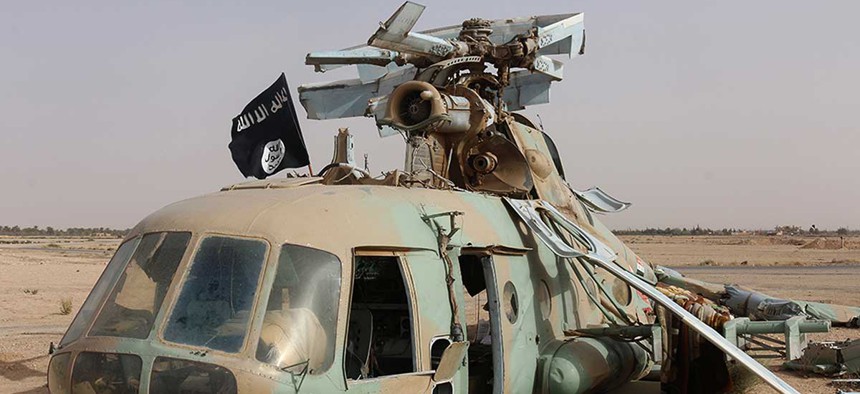 An Islamic State flag sits on a damaged helicopter at Tadmur military airbase in May.
