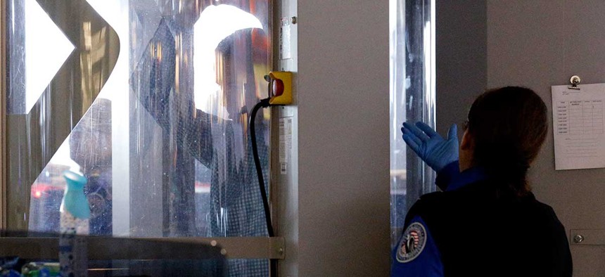 A traveler undergoes a body scan as a TSA agent looks on at a security checkpoint area at Chicago's Midway International Airport in 2014. 