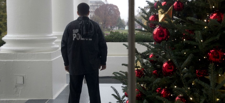 A member of the Secret Service Uniform Division looks out from the North Portico during a preview of the 2015 holiday decor at the White House in early December. 