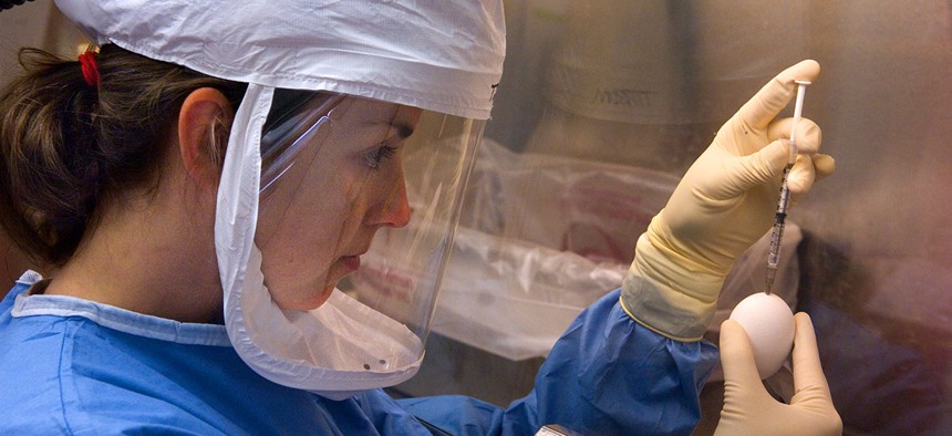 A microbiologist in CDC's Influenza Branch conducts an experiment inside a biological safety cabinet.