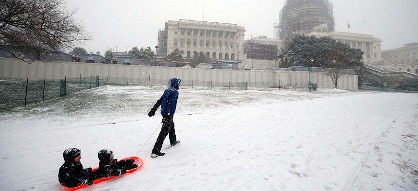 Ben Cichy pulls a sled with his sons Adrian, 18-months-old, and Logan 3, inside as they head for sledding in the snow on Capitol Hill Friday.
