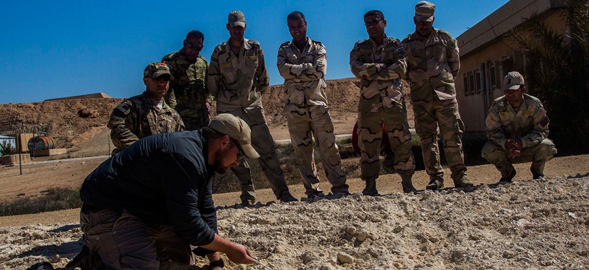 A civilian contractor works with Iraqi soldiers in 2015.