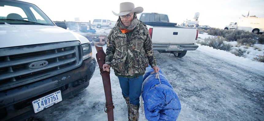 LaVoy Finicum carries his rifle after standing guard all night at the Malheur National Wildlife Refuge in January.