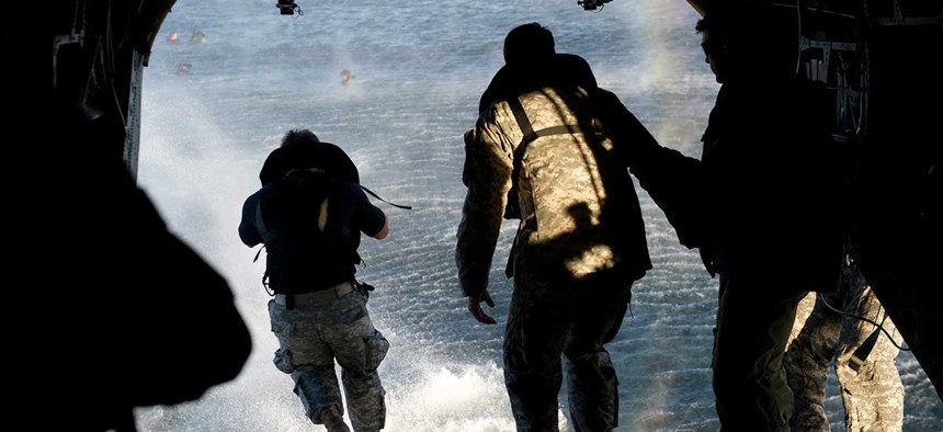 Green Berets exit a CH-47 Chinook helicopter into a bay during helocast training in 2013 in Florida.
