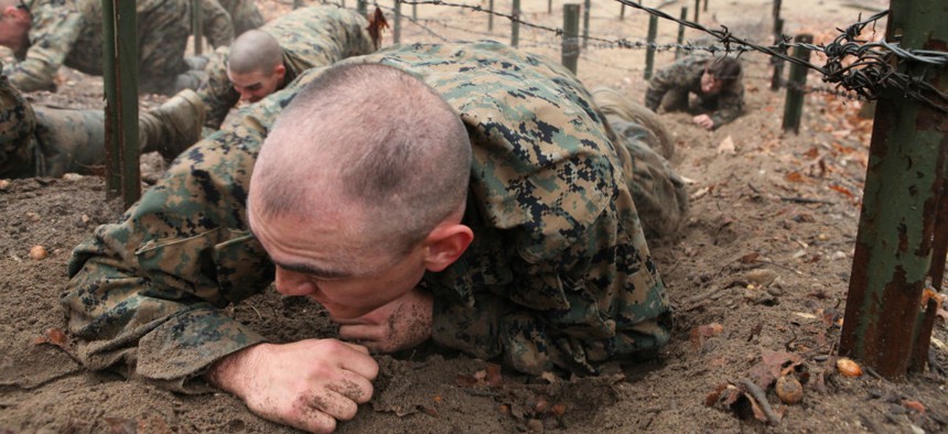 A Marine enrolled in Officer Candidate School low-crawls under a barbed wire obstacle on the Montford Point Challenge obstacle course at Marine Corps Base Quantico, Va.