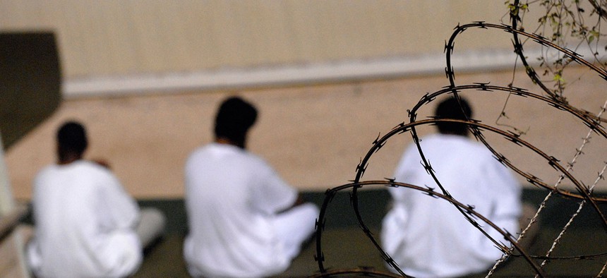 A small group of detainees housed in Guantanamo sit on prayer rugs in 2009