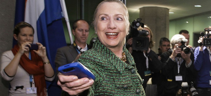 Then-Secretary of State Hillary Rodham Clinton hands off her mobile phone after arriving for a meeting in The Hague, Netherlands, Dec. 8, 2011.