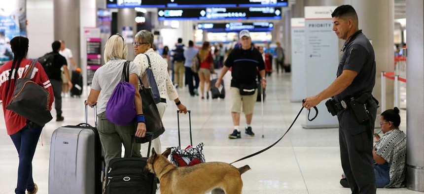 A K-9 handler with the Miami-Dade police department patrols at Miami International Airport Friday.