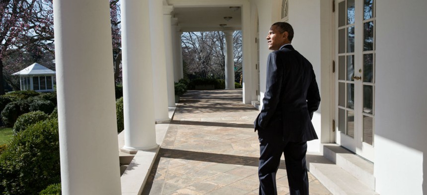 President Obama looks out over the Rose Garden as he walks along the Colonnade of the White House.