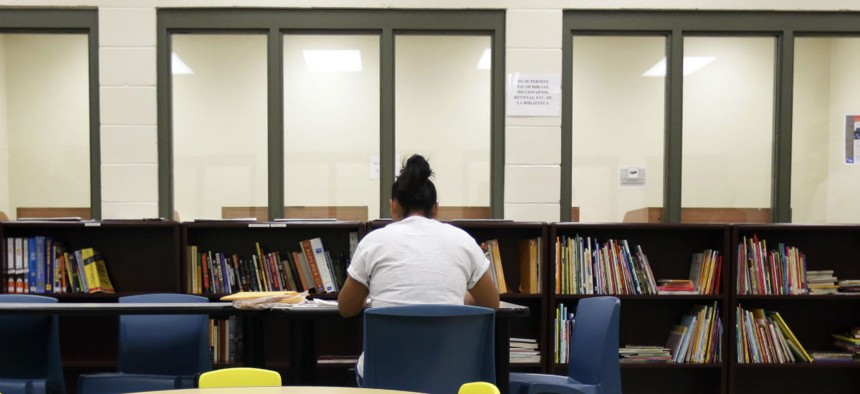 A woman uses the library at a temporary home for immigrant women and children detained at the border, in Karnes City, Texas.