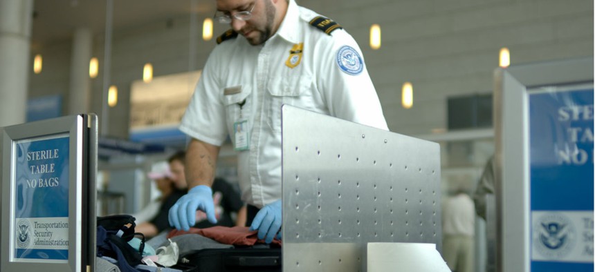 A TSA agent searches luggage at an airport. 