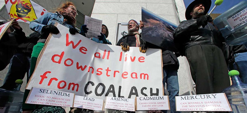 Demonstrators chant and hold signs behind a display of coal ash and the chemicals in it during a protest near Duke Energy's headquarters in Charlotte in 2014.