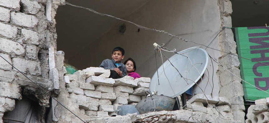Children peer from a partially destroyed home in Aleppo, Syria in February.