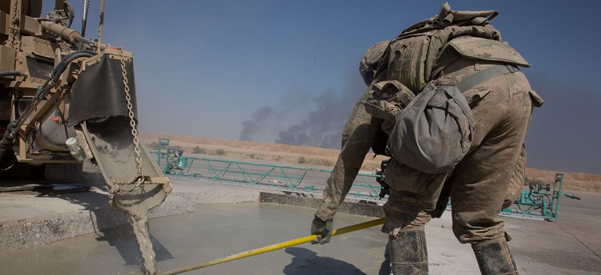 An airman assigned to the 1st Expeditionary Civil Engineering Group levels poured concrete in a trench during runway repair operations at Qayyarah West airfield, Iraq, Oct. 8, 2017. 