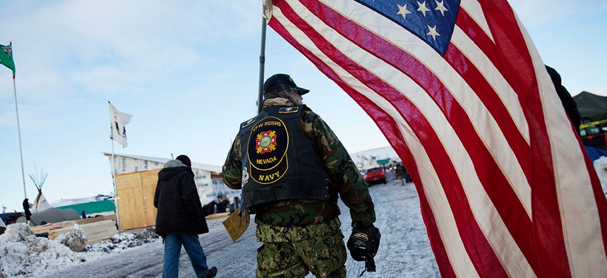 Navy veteran Rob McHaney walks with an American flag at the Oceti Sakowin camp where people have gathered to protest the Dakota Access oil pipeline in Cannon Ball, N.D., on Sunday.