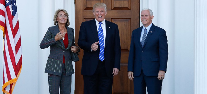 Donald Trump calls out to media as he Vice President-elect Mike Pence and Betsy DeVos pose for photographs in New Jersey in November.