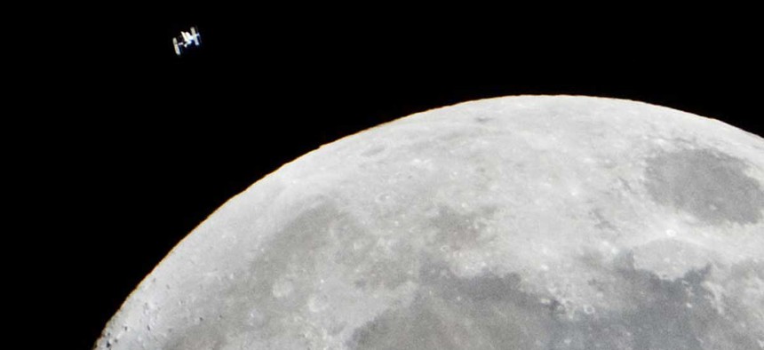 The International Space Station passes by the moon in 2015.