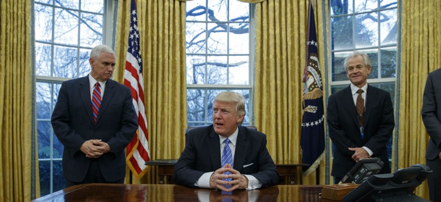 Vice President Mike Pence, left, and National Trade Council adviser Peter Navarro, right, wait for President Donald Trump to sign executive orders on Monday.