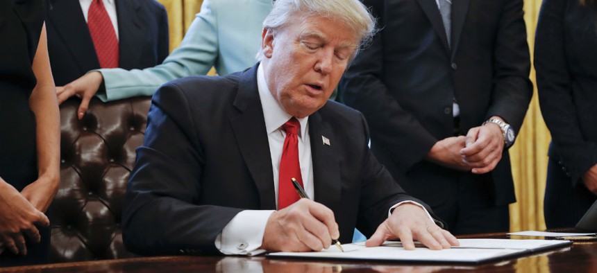 Trump signs the executive order to cut regulations on Monday. 