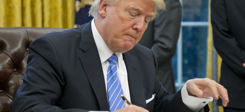 President Trump signs orders including the hiring freeze on Monday. 
