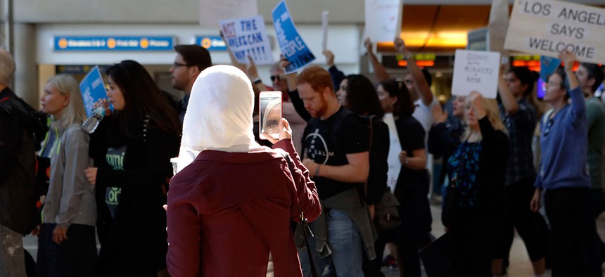 A traveler records demonstrators as they march through Tom Bradley International Terminal as protests against President Donald Trump's executive order banning travel from seven Muslim-majority countries continue at Los Angeles International Airport Sunday