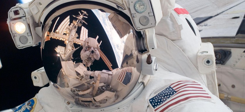 STS-124 Mission Specialist Mike Fossum participates in the mission's first spacewalk. Visible in the reflections of his helmet visor are various components of the station, Earth's horizon and astronaut Ron Garan.