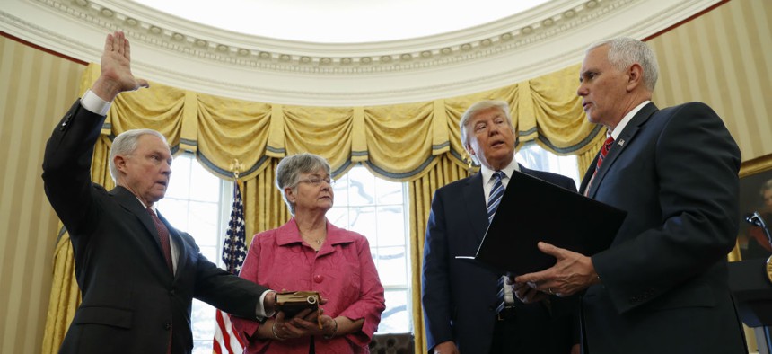 President Donald Trump watches as Vice President Mike Pence administers the oath of office to Attorney General Jeff Sessions, accompanied by his wife Mary on Feb. 9.