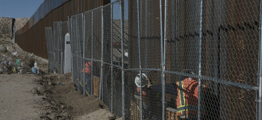 Workers raise a taller fence in the Mexico-US border separating the towns of Anapra, Mexico, and Sunland Park, New Mexico, in January.