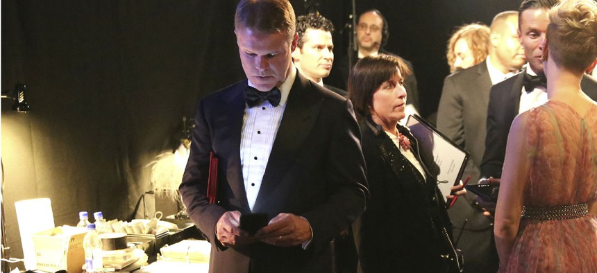 PricewaterhouseCoopers accountant Brian Cullinan, center, holds red envelopes under his arm while using his cell phone backstage at the Oscars. 
