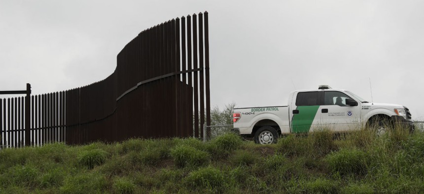 In this Nov. 13, 2016, photo, a U.S. Customs and Border Patrol agent passes along a section of border wall in Hidalgo, Texas. 