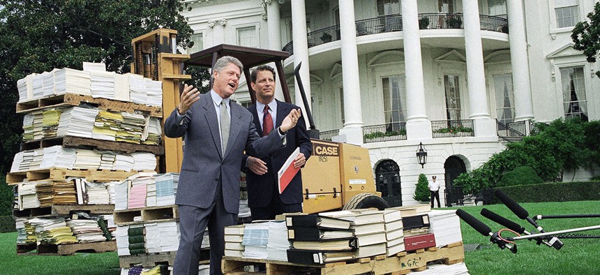 Bill Clinton gestures as he and Al Gore stand by a forklift with reams of federal bureaucratic rules and regulations outside the White House in 1993.